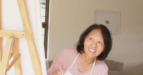 Senior Asian Woman Joyfully Painting at Home