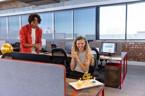 Coworkers celebrating birthday in open office with cupcakes