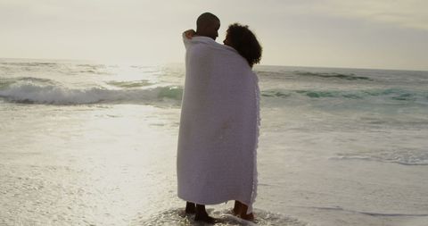 Romantic Couple Embracing Under Blanket by Oceanside