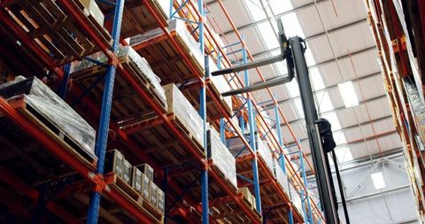 High-bay warehouse pallet racking with forklift mast and stacked pallets for logistics