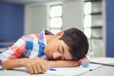 Teen student napping on classroom desk during study session