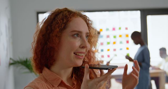 Smiling Redhead Woman Using Voice Command on Smartphone in Modern Workspace - Download Free Stock Images Pikwizard.com