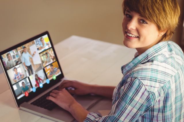 Smiling caucasian girl using laptop for video call, with diverse high school pupils on screen. communication technology and online education, digital composite image.