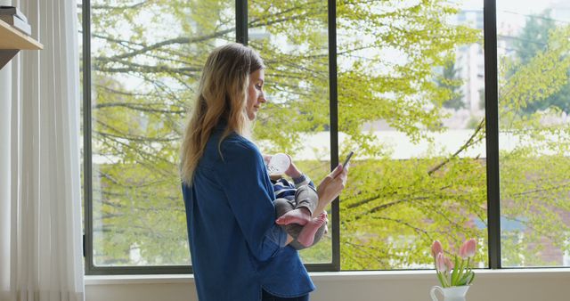 Mother Holding Baby While Using Smartphone in Bright Living Room - Download Free Stock Images Pikwizard.com