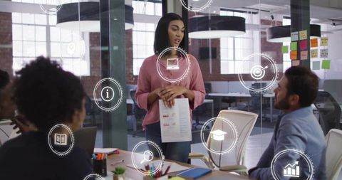 Female leader presenting business report to team in modern glass office with tech icons