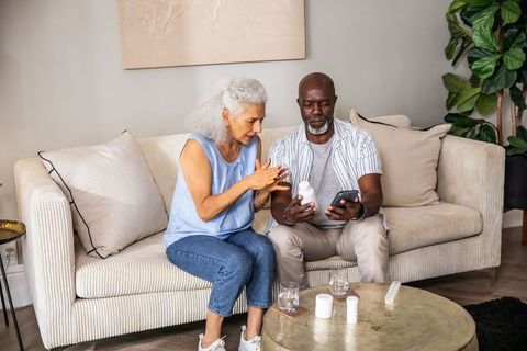 Senior Couple Using Smartphone for Medication Instructions in Cozy Living Room