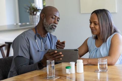 Black healthcare professional guiding older black woman through medication plan on tablet