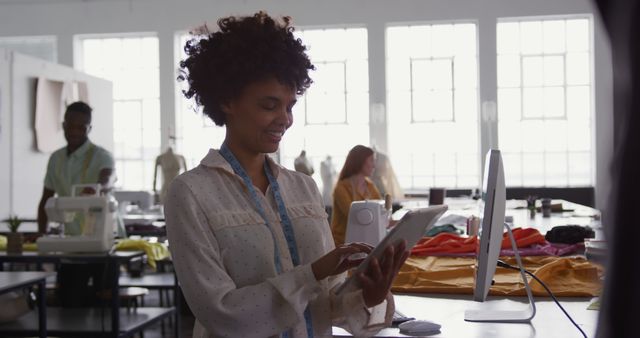 Designer Using Tablet in Fashion Studio with Colleagues Working - Download Free Stock Images Pikwizard.com