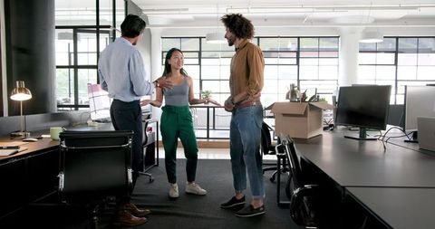 Diverse team collaborating while unpacking in modern office space