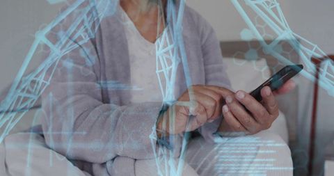 Senior woman tapping smartphone in cozy bedroom with blue holographic wireframe overlay