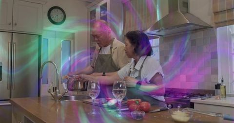 Chinese couple stirring and preparing dinner at modern kitchen island with tomatoes