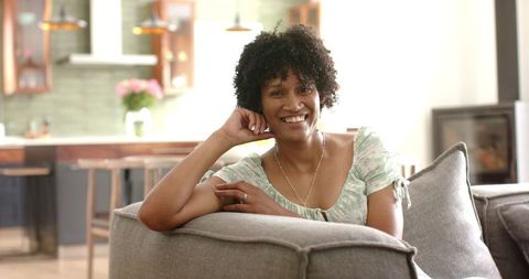 Smiling African American Woman Relaxing on Couch in Sunny Living Room