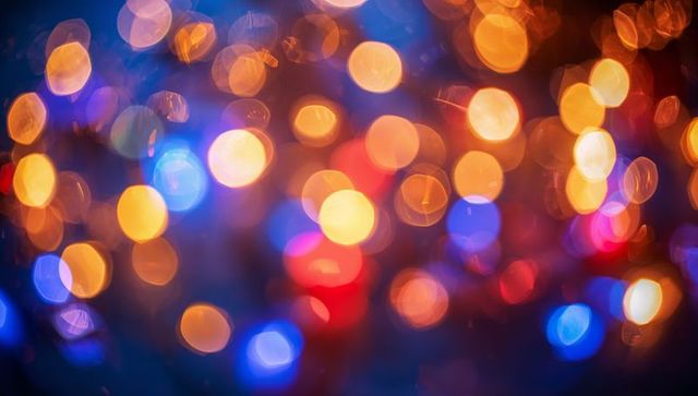 Glowing bokeh lights in warm blue and orange tones creating festive abstract background
