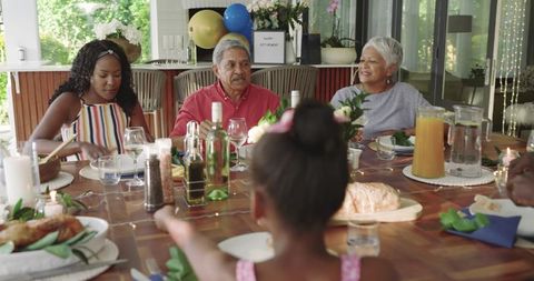 Multigenerational family sharing joyful outdoor luncheon on sunlit patio