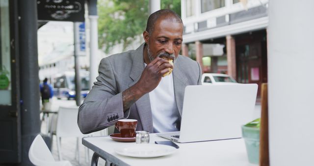 Businessman Eating Sandwich While Working on Laptop at Outdoor Café - Download Free Stock Images Pikwizard.com