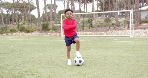 Confident Boy Practicing Soccer on Grass Field