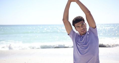 Young Man Stretching at Sunny Beach in Casual Attire - Download Free Stock Images Pikwizard.com