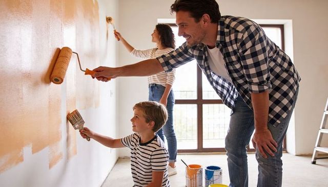 Family Painting Project Together: Father and Son Rolling Wall While Mother Paints Weekend DIY