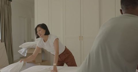 Couple Unpacking and Making Bed in New Home, Teamwork and Togetherness