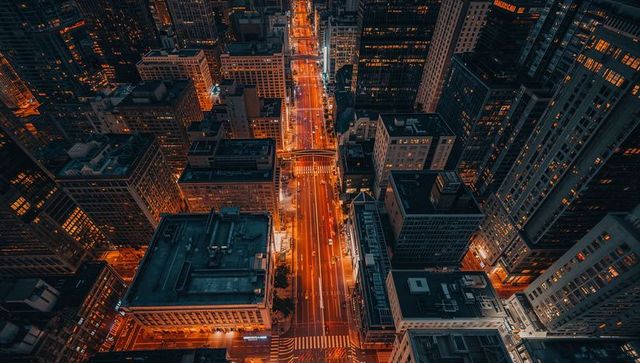 Aerial night city avenue glowing with neon light trails and rooftop geometry