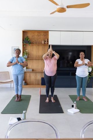 African american women practicing standing yoga pose in bright minimalist home living room