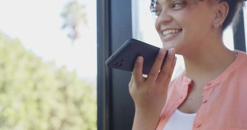 Woman Using Smartphone Voice Assistance Near Large Window