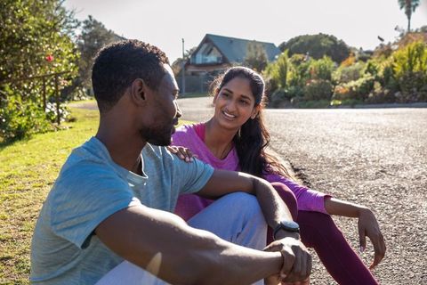 Diverse couple resting on suburban street after workout