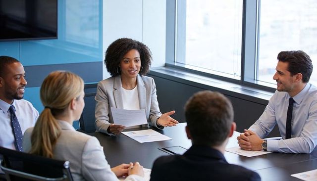 Woman presenting quarterly report to team in modern boardroom during collaborative meeting