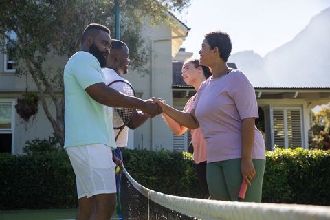 Diverse tennis players shaking hands across scenic outdoor court