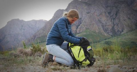 Young Adventurer Organizing Gear in Scenic Mountain Pass