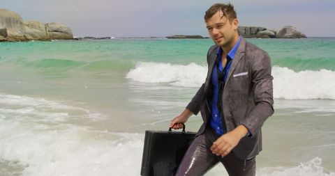 Businessman walking in ocean wearing wet suit with briefcase