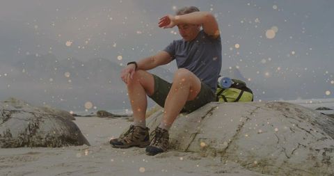 Tired Hiker Resting on Rocky Shore Amidst Calm Beach Scenery