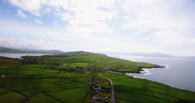 Aerial view of a picturesque coastal landscape with lush green fields and a serene body of water, with copy space. The patchwork of farmland stretching to the coastline creates a tranquil and idyllic rural scene.