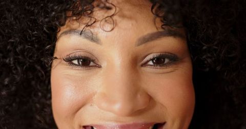 Portrait of smiling woman with curly hair and confident expression