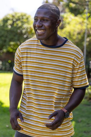 Smiling African American Man Wearing Striped T-Shirt Enjoying Sunlit Backyard Moment