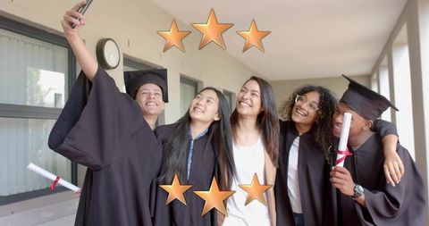 Graduation day selfie with graduates and mentor celebrating diplomas on campus corridor