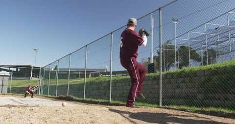 Baseball players practicing pitch and catch outdoors on sunny day