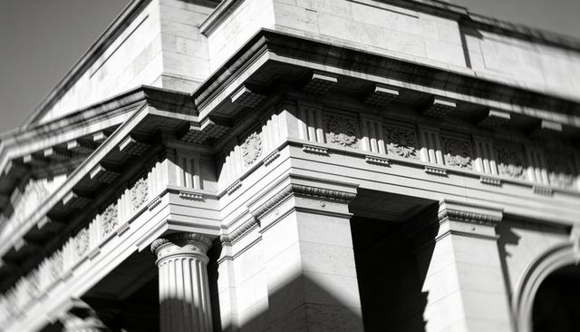 Neoclassical stone facade corner with fluted column, dentil cornice and ornate frieze
