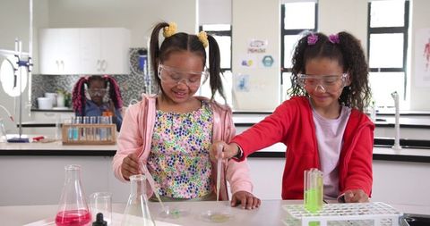 Young female students conducting chemistry experiments in school lab