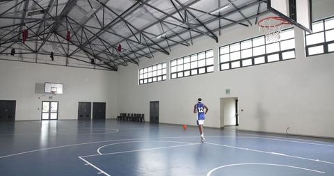 Basketball player dribbling in spacious indoor gymnasium