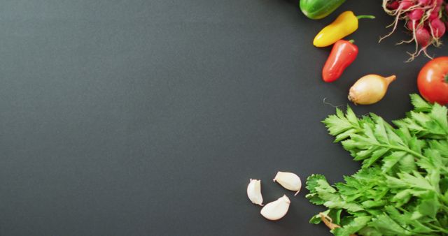 Ideal for use in culinary blogs, healthy eating articles, or cooking websites. Image featuring fresh vegetables and herbs on a black background, including garlic cloves, leafy cilantro, onions, radishes, a tomato, and various colorful bell peppers.
