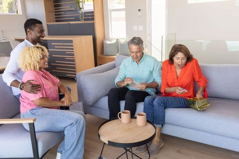 Multigenerational diverse family opening gift together in modern cozy living room