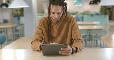 African American Man Using Tablet in Modern Coworking Cafeteria, Casual Remote Work