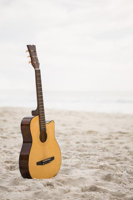 Acoustic guitar standing in the sand - Download Free Stock Photos Pikwizard.com