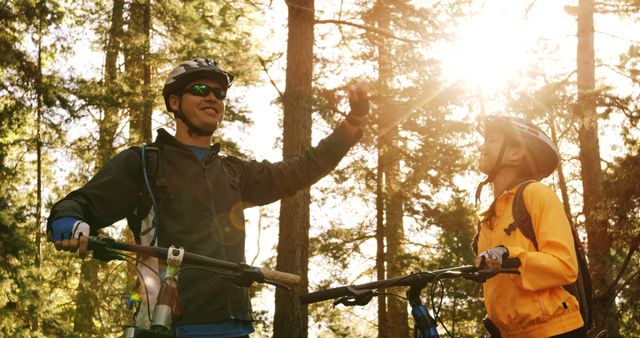 Two young adults celebrate with a high-five during a mountain biking trip in the forest. - Download Free Stock Photos Pikwizard.com