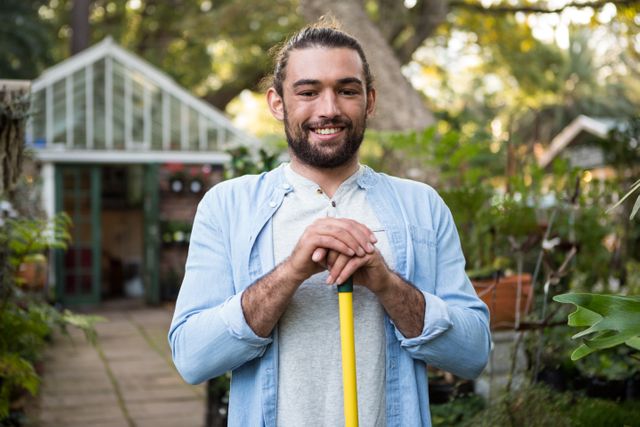 Portrait of happy young male gardener with work tool at garden