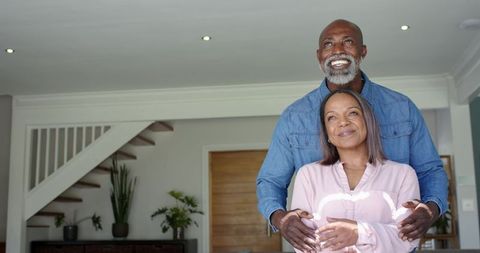 Mature couple embracing in modern home entryway, smiling, showing warmth and connection