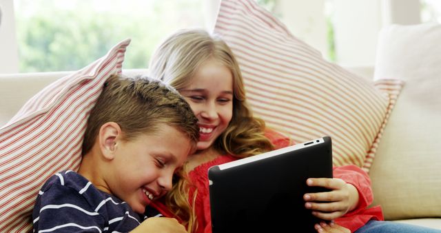 Siblings Relaxing on Couch Sharing Tablet Smiling - Download Free Stock Images Pikwizard.com