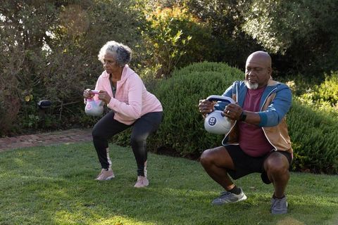 Senior Couple Performing Kettlebell Squats in Garden