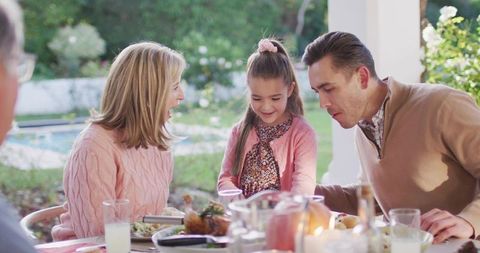 Young Girl Serving Dessert While Parents React During Backyard Alfresco Meal